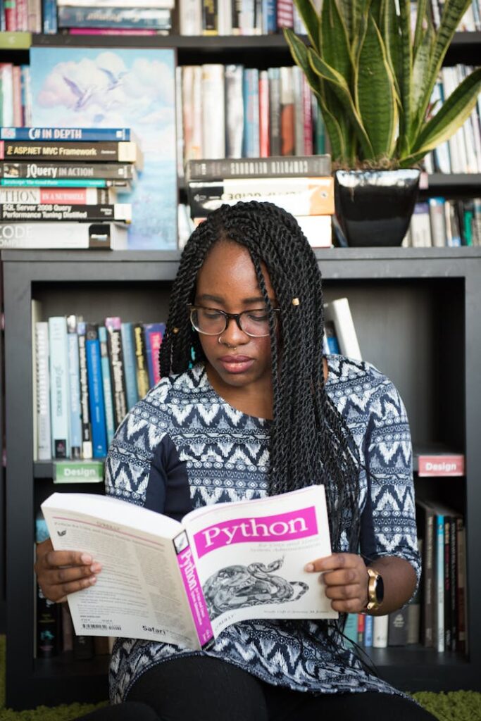 African American woman studying Python programming in a library setting.